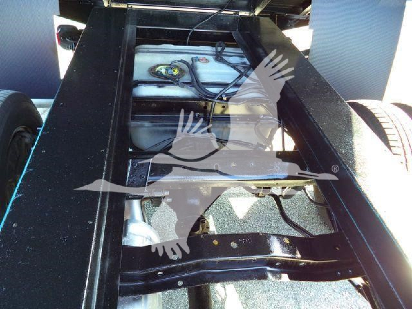 Ford E-450 chassis undercarriage showing fuel tank and frame rails with dual rear wheels visible.
