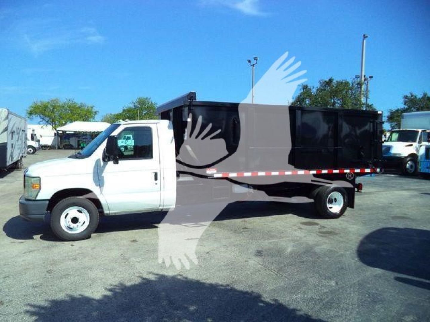 Dump truck with white cab and black dump body, side view showing cylindrical wheel wells and reflective stripes, Ford E-Series chassis.