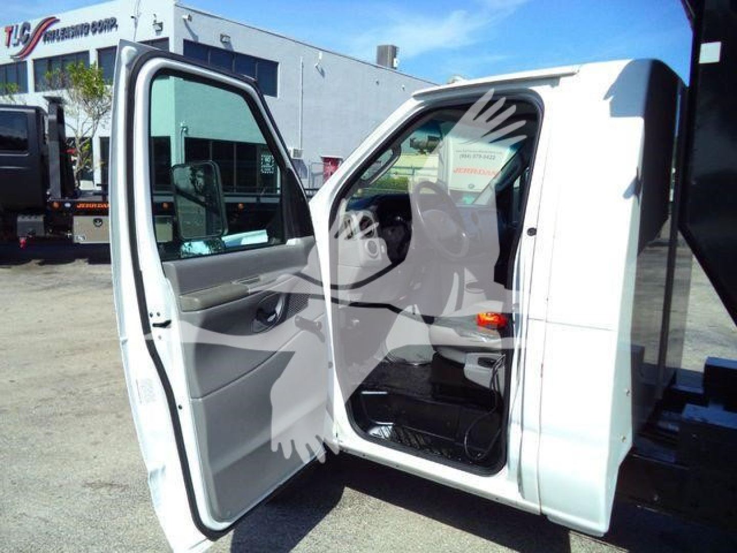 Ford E-450 dump truck cab with door open, showing interior and passenger seat; no visible text legible on badges or labels.