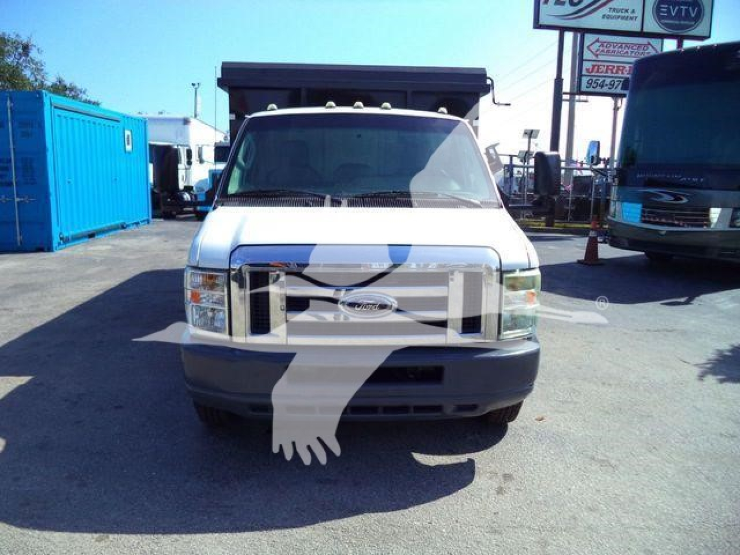 Ford E-450 dump truck front view showing grille badge and large cargo bed in raised position.