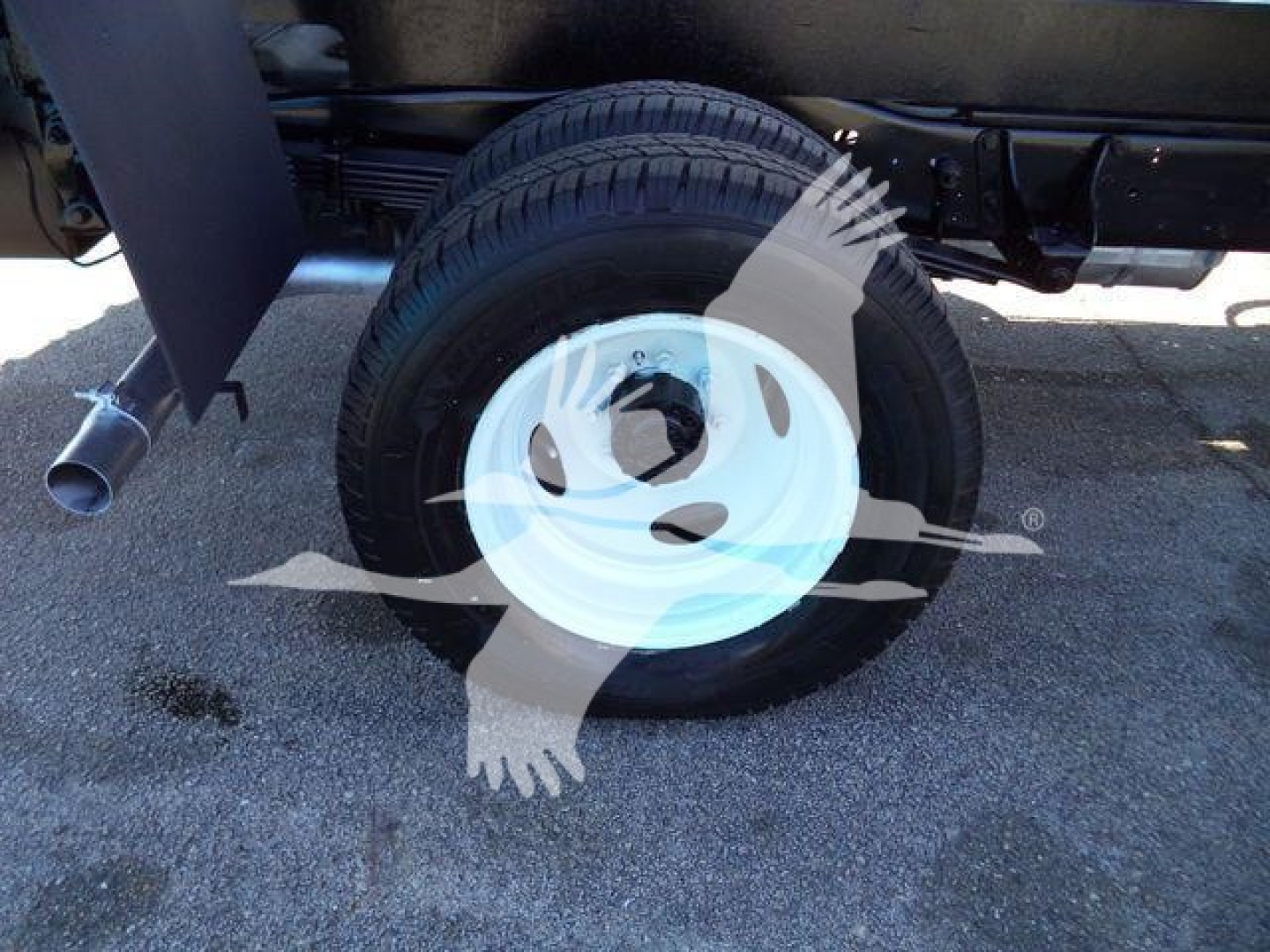 Ford E450 truck wheel and undercarriage with spare white steel rim and tire side view.