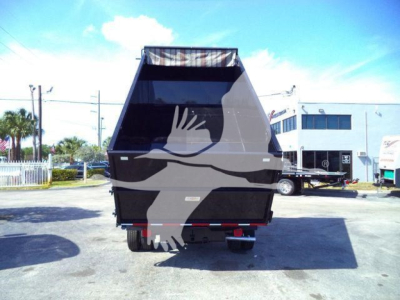 Rear view of a 2011 Ford E450 dump truck with black dump body, oversized bed, and dual rear wheels in a dealership lot.