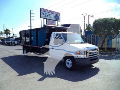 Ford E-450 dumping truck shown in a dealership lot with blue dump body and white cab; sign in background reads TLC Truck Sales Center.