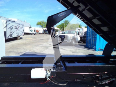 Ford E450 dump truck undercarriage hitch area with hydraulic components and white reservoir visible.