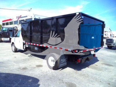 Ford E450 dump truck rear view showing black dumping bed and white cab with stock number T57118 PB.