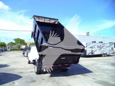 Ford E-450 dump truck rear view with raised dump bed in a dealership lot.