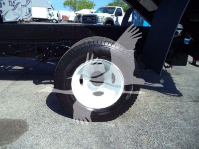 Ford E-450 dump truck wheel and undercarriage with partial view of chassis; visible tire and white steel wheel. No legible model text.