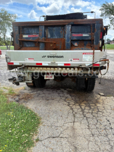 Dump truck bed with Swenson logo and rear view showing tailgate and safety decals.