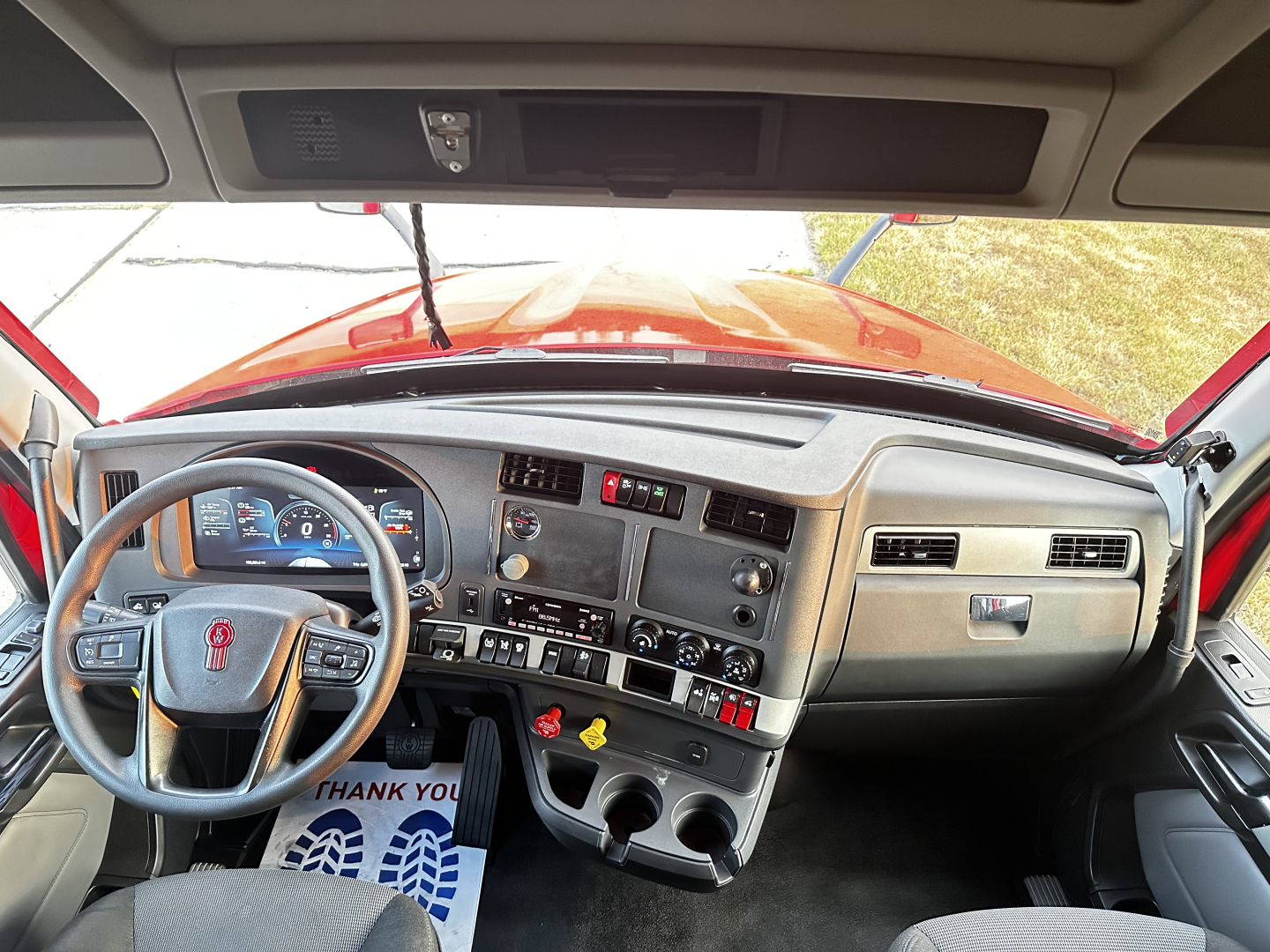 Kenworth T680 cab interior dashboard and steering wheel with instrument cluster, center console, cup holders, and control switches visible.