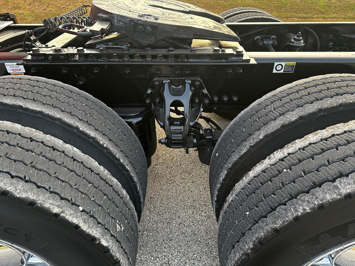 Kenworth truck chassis drivetrain area with dual rear axles and fifth-wheel mounting plate visible. No readable labels or fluid specs.