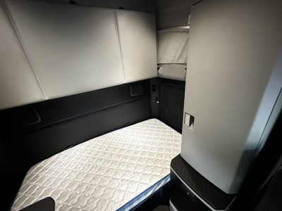 Kenworth T680 sleeper cab interior view with quilted mattress and side storage panels.