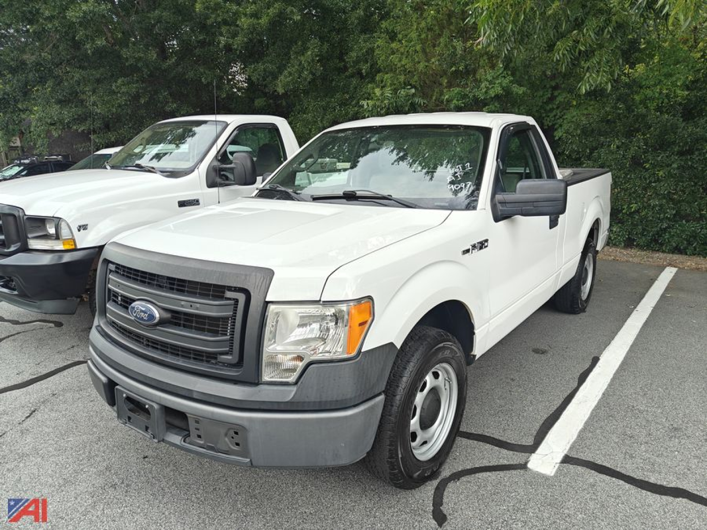 Ford F-150 pickup truck in a parking lot, white cab with gray bumper and black mirrors, 2014 model year visible by badge on door.