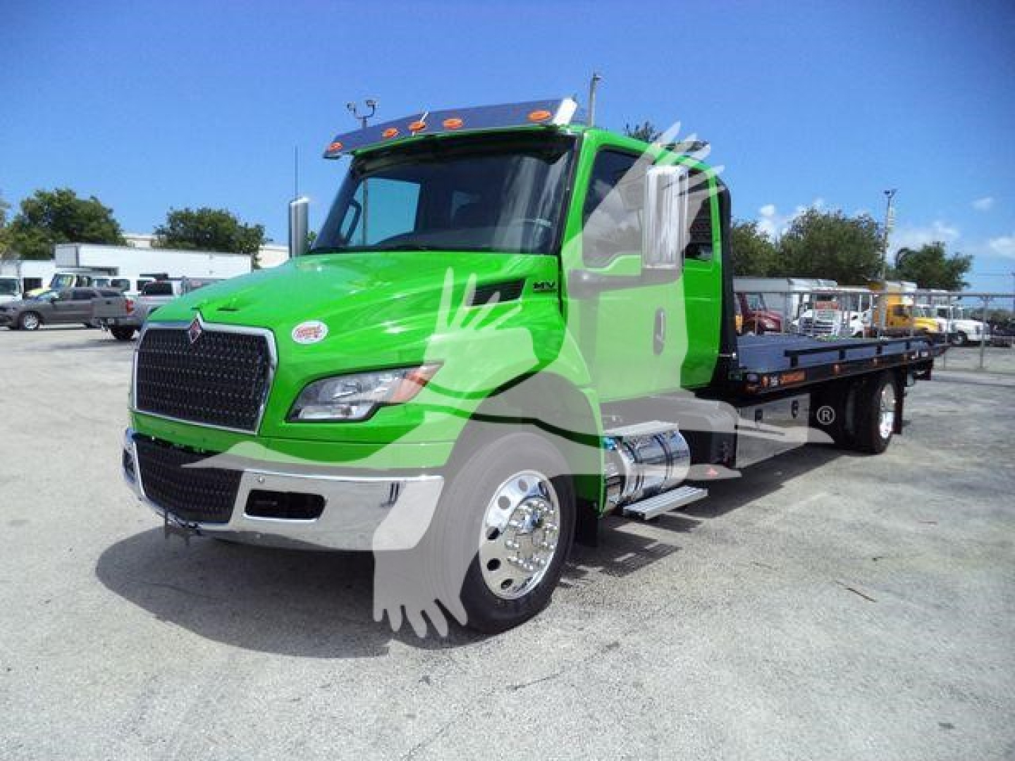 Green 2027 International MV rollback truck side view showing flatbed; stock number J24111; front grille and chrome bumper visible.
