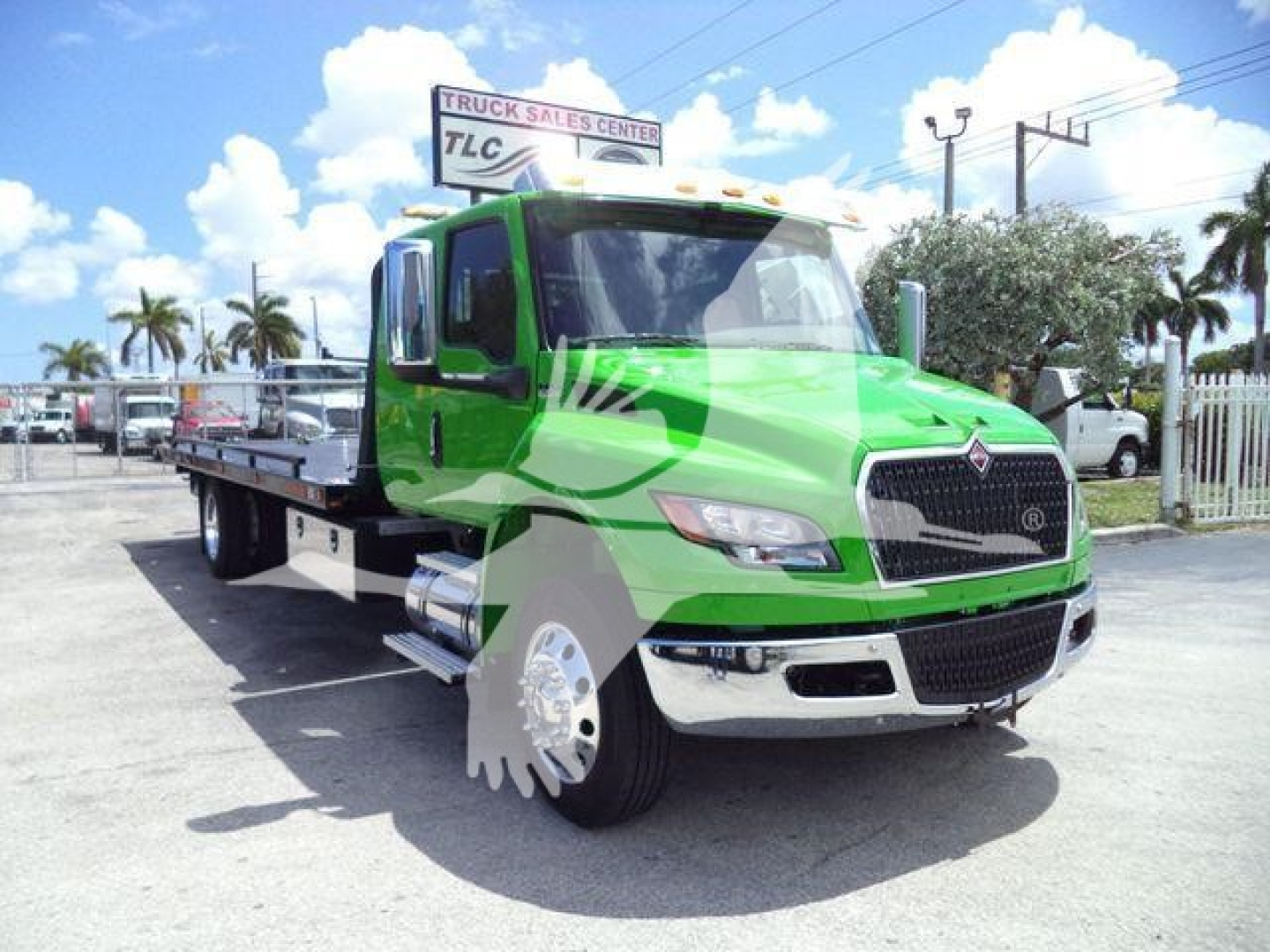 Green International MV tow truck in a lot showing flatbed with chrome bumper and distinctive grille.