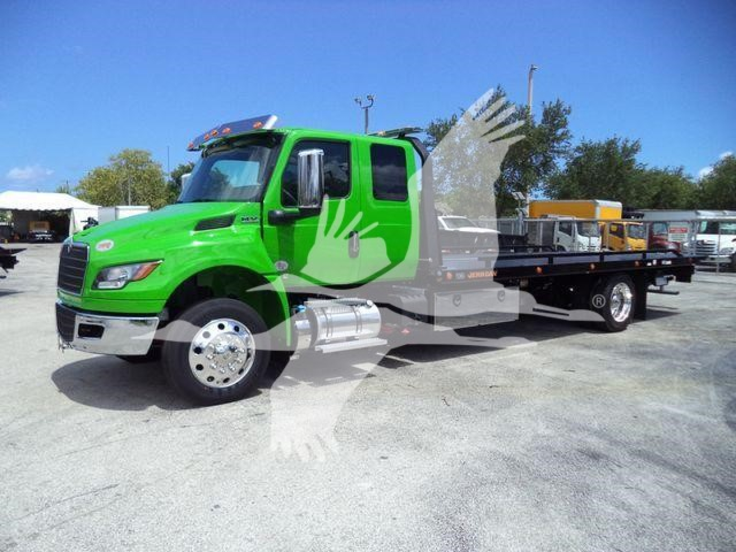Green International MV rollback truck showing cab and flatbed with stock number J24111 visible in listing.