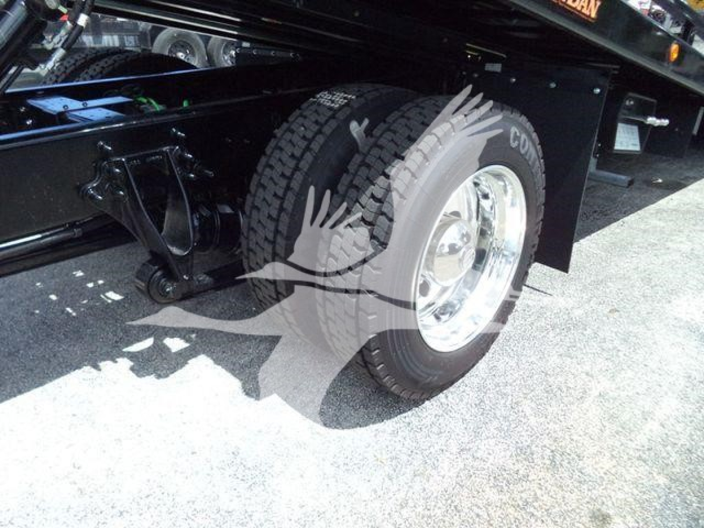 Truck bed view showing a dual rear wheel on an International MV rollback chassis with tire and wheel visible.