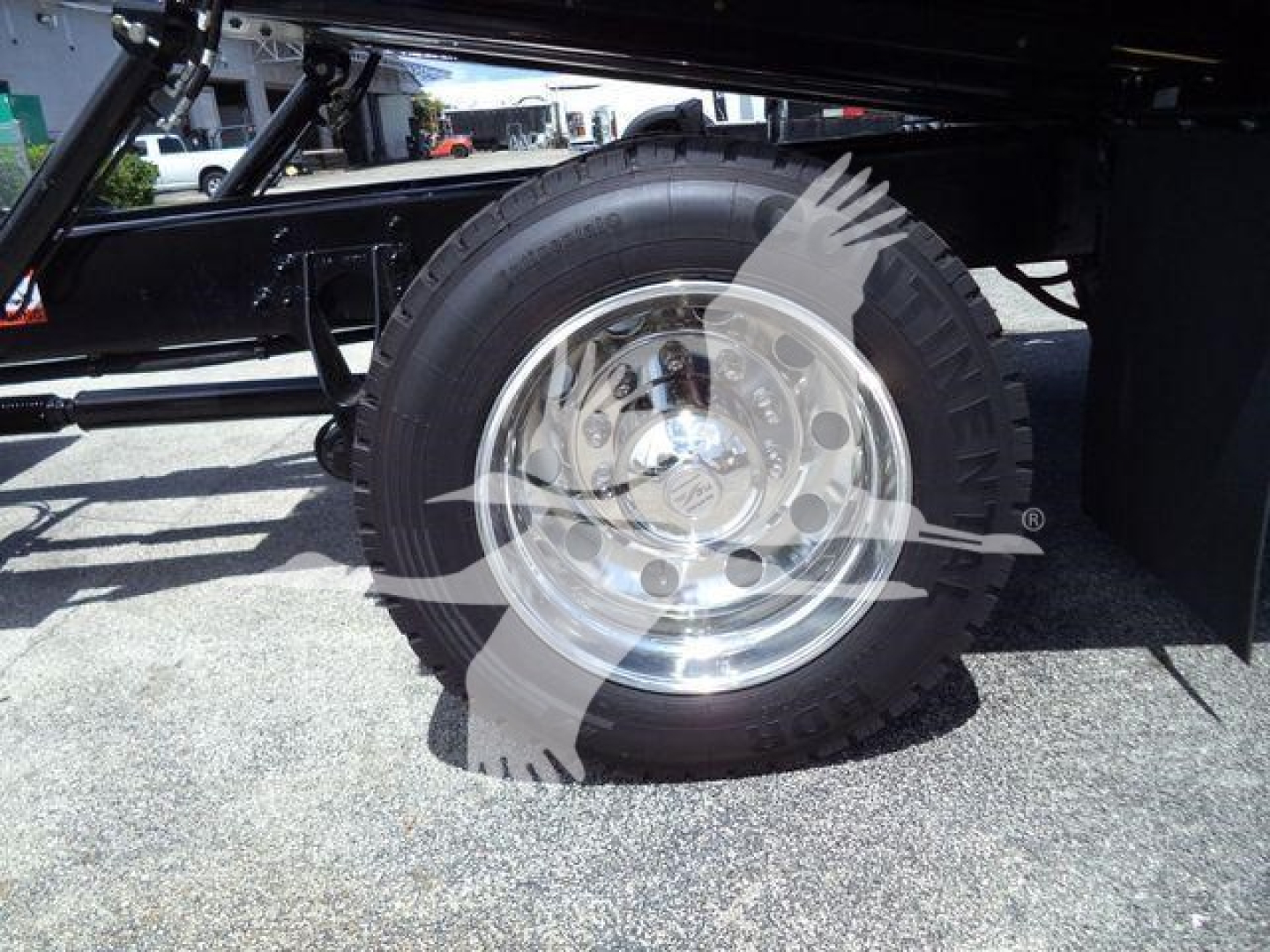 Truck wheel and rim in a rollover truck chassis showing polished aluminum rim and large off-road tire.