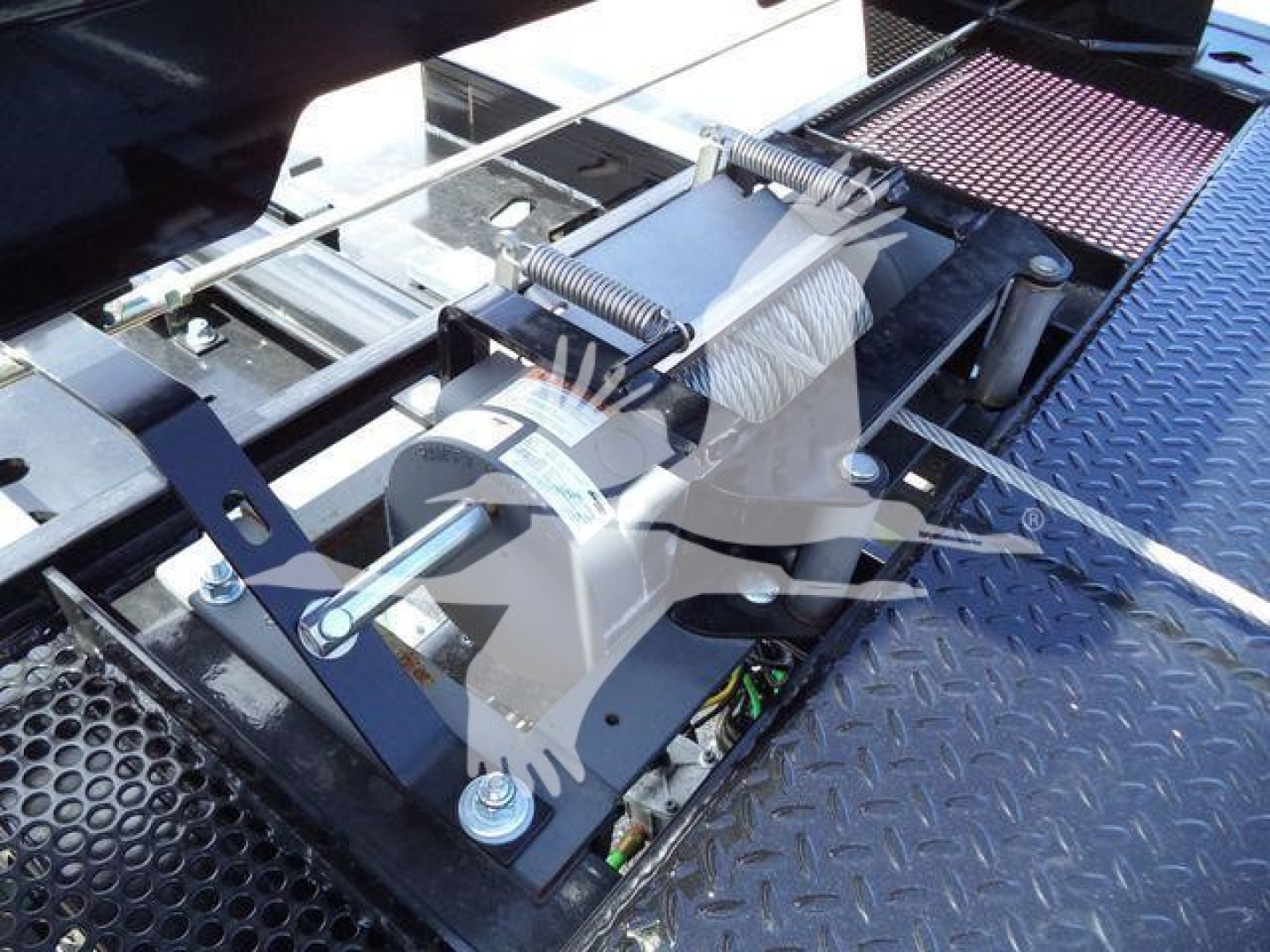 Winch assembly with cable and springs on a platform, mounted on a truck chassis, with diamond plate surface