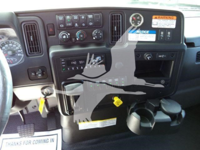 Dashboard of a new International MV rollback truck showing control panel, gauges, cup holders, and warning stickers.