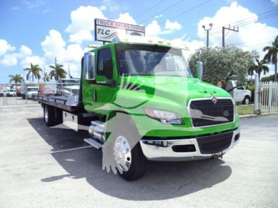 Green International MV tow truck in a lot showing flatbed with chrome bumper and distinctive grille.