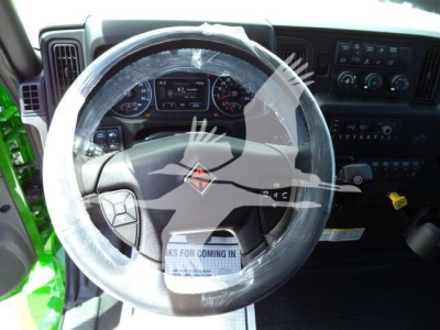 Interior of a truck cab with steering wheel and dashboard visible; plastic-wrapped steering wheel cover; dashboard gauges and control panels with various dials and switches.
