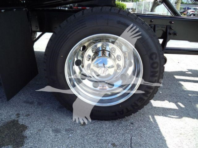 Wheel and chrome hubcap on a truck with reflective surface showing lug nuts and tire treads.
