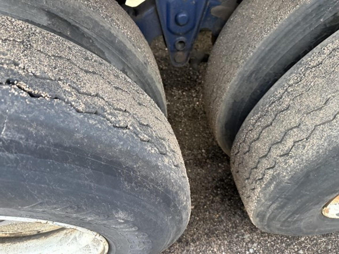 Trailer wheel tires on a Transcraft flatbed trailer axle showing tread wear and dual rear tires.