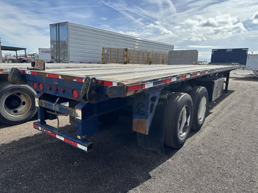 45' steel closed tandem flatbed trailer with fork lift kit, viewed from rear-left side, blue frame with dual axles and rear bumper.