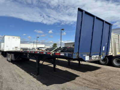 Flatbed trailer with blue steel end cap showing open flat deck and fork lift kit area. No readable labels visible.