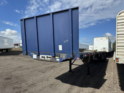 Flatbed trailer rear view showing blue Transcraft steel 45' closed tandem with fork lift kit components and rear bumper stickers.