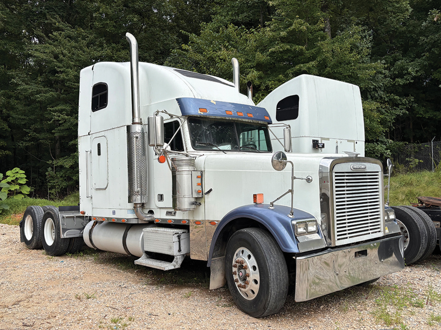 Freightliner FLD13264T Classic XL sleeper cab tractor showing chrome vertical exhaust stacks and large grille.