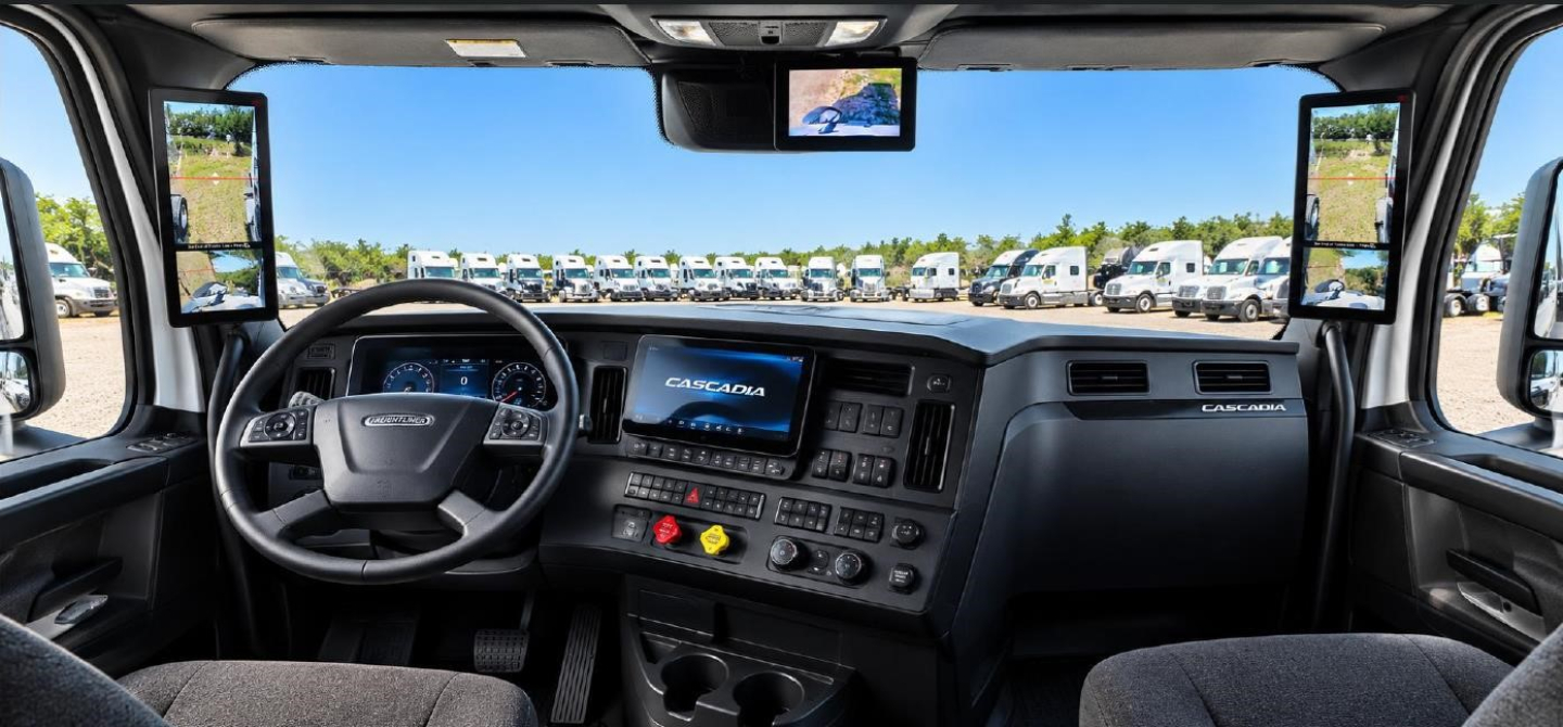 Dashboard and steering wheel of a new Freightliner Cascadia 126 truck cab showing modern instrument cluster and infotainment screen.