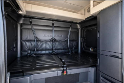Freightliner Cascadia 126 cargo area with netting and folded bunk bed behind seating