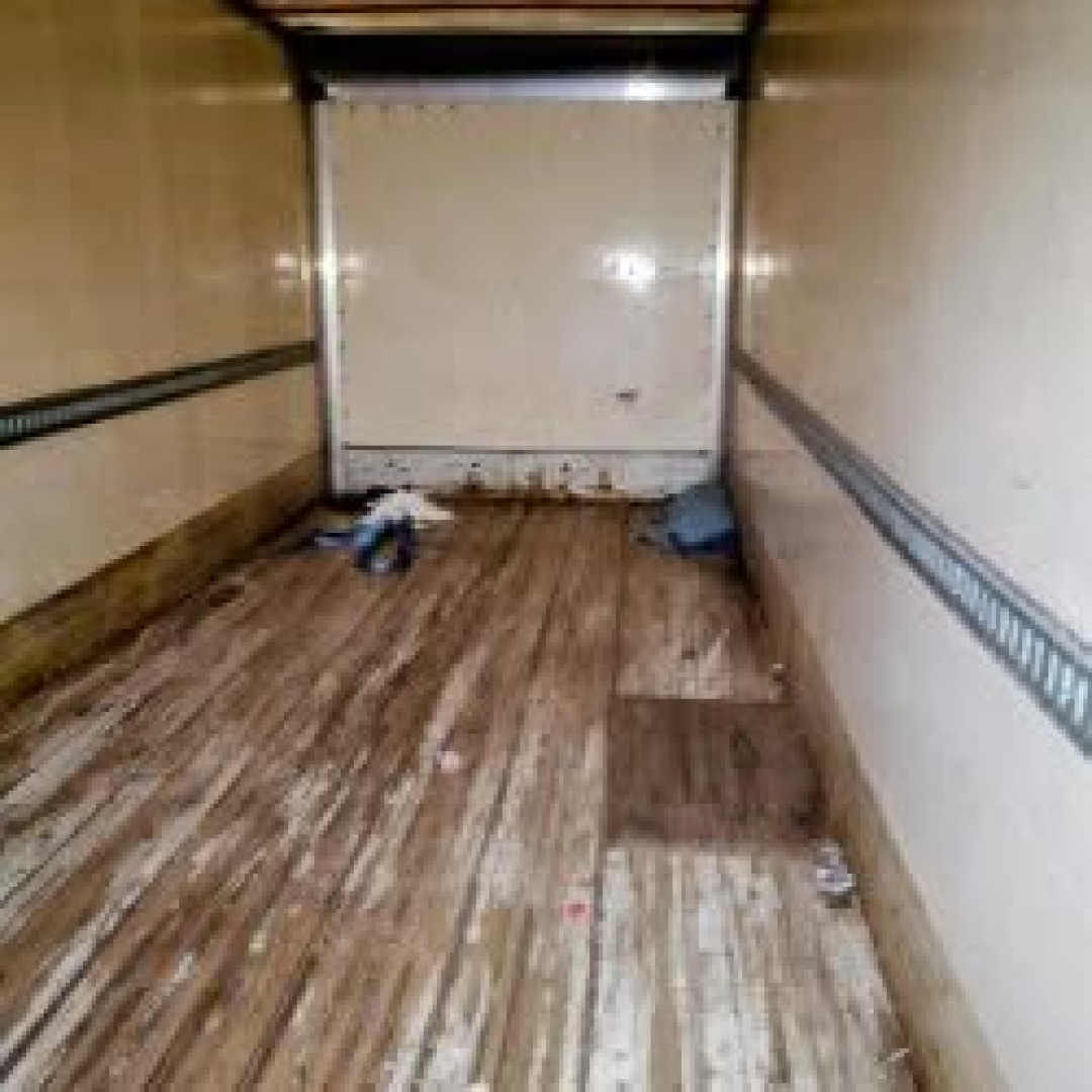 Truck cab interior empty trailer showing wooden floor with debris.