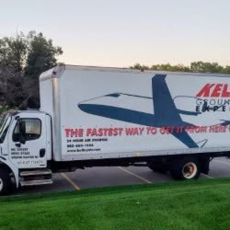 Truck side view showing Freightliner M2 106 box truck with graphics and logo on the cargo box.