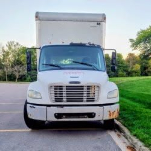 White Freightliner M2 106 box truck front view with grille, headlights, and bumper; windshield wipers and side mirrors visible.