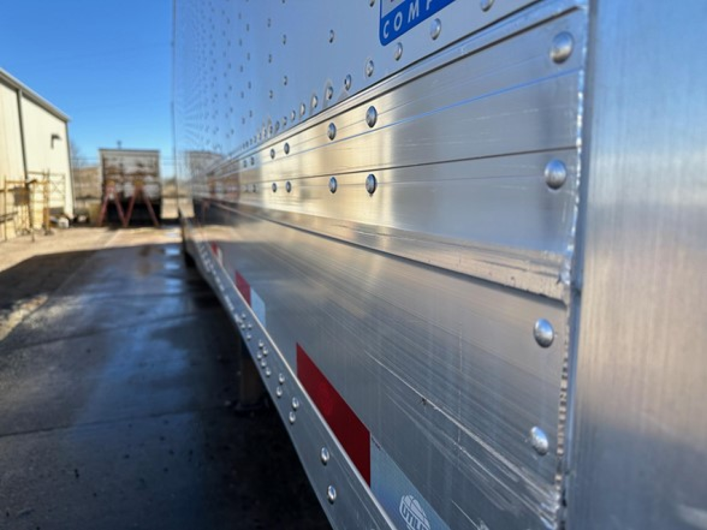 Aluminum trailer side with riveted panels and reflective striping, view along length of Utility 4000Dx trailer.