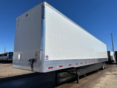 Trailer side view showing Utility 4000Dx cargo trailer with white panel exterior and black undercarriage, front landing gear, and rear dual axles.