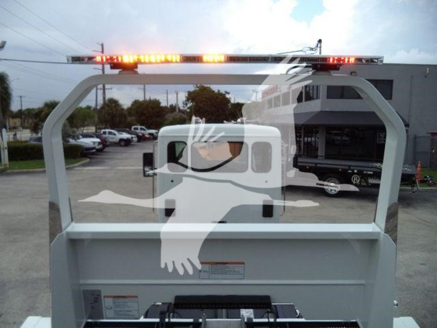 Kenworth truck rollback bed with rear cab window, warning labels, and light bar on top; visible text includes stock and category hints but not fully legible.