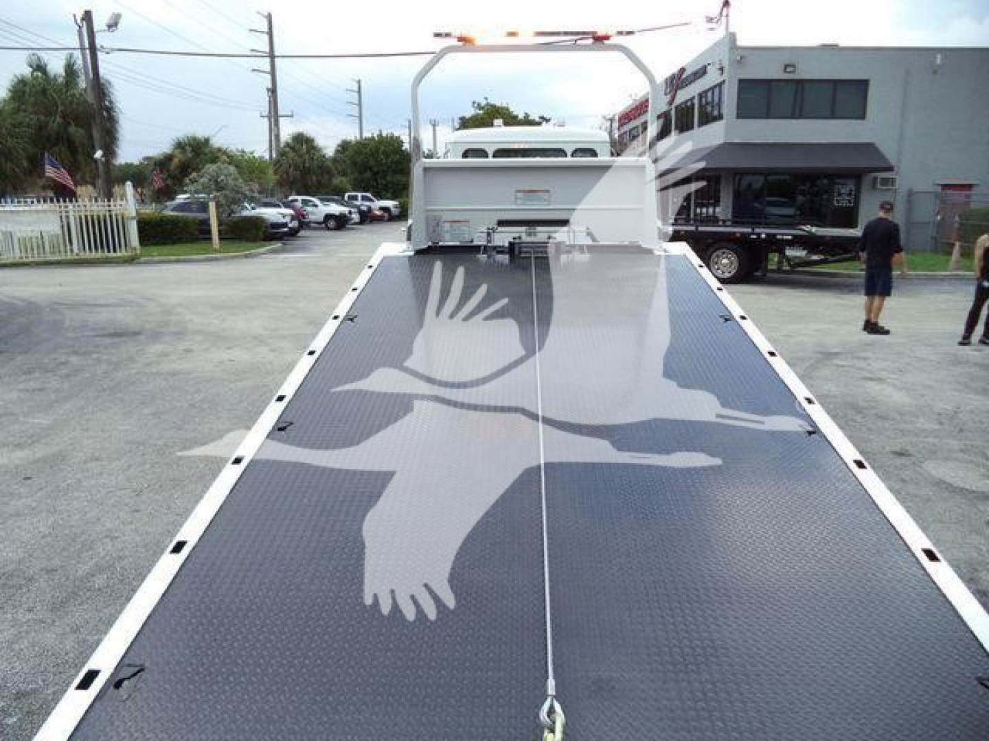 Truck bed in a 2025 Kenworth T280 rollback showing wide diamond-plate platform with bird graphic and rear winch/lift assembly.