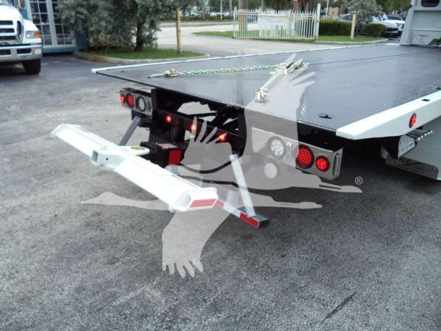 Kenworth T680 rollback bed rear with tow hitch and wheel-lift assembly visible, black and white color scheme, hydraulic components and taillights.