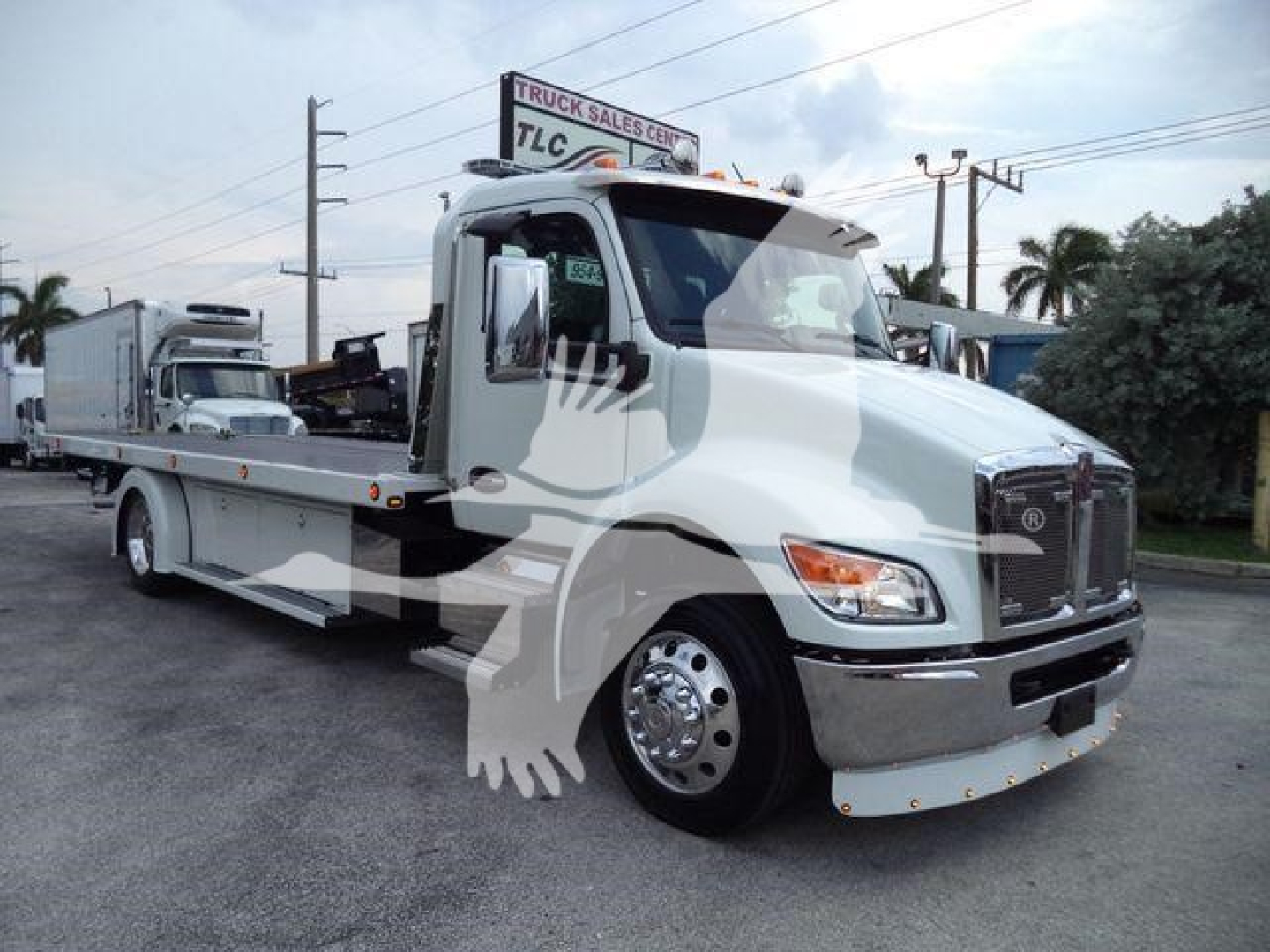 Kenworth T280 rollback tow truck in white, front three-quarter view with chrome bumper and mirrors, wheel covers visible.