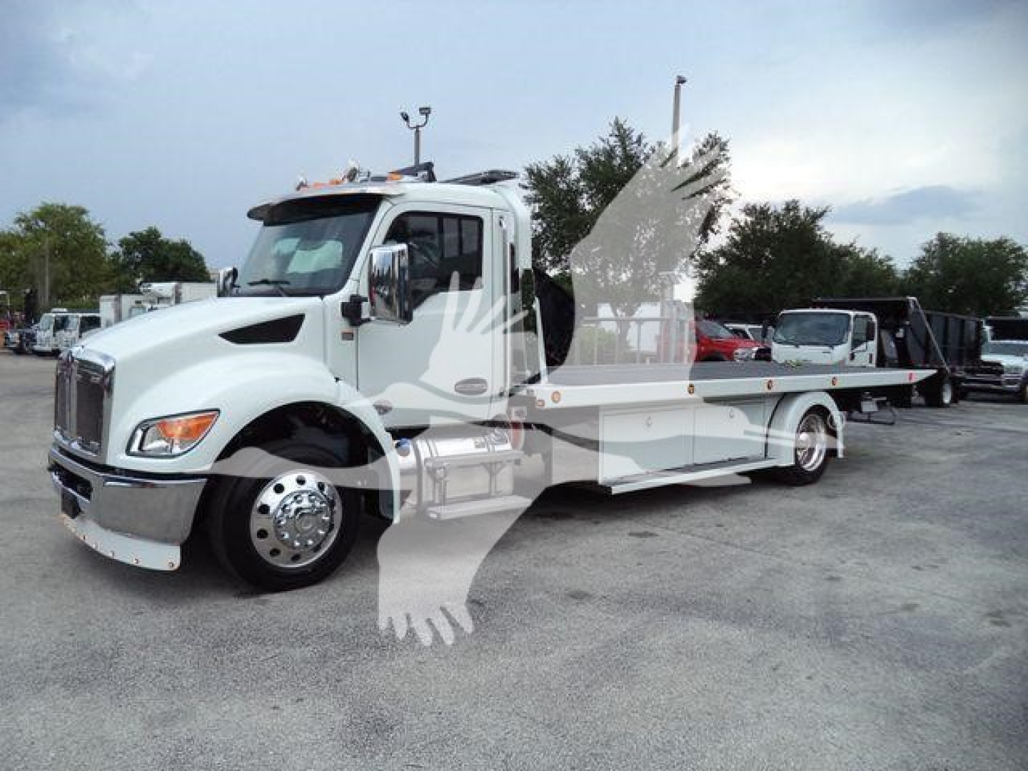 Kenworth T280 rollback truck in a lot with white cab and flatbed, daylight setting.