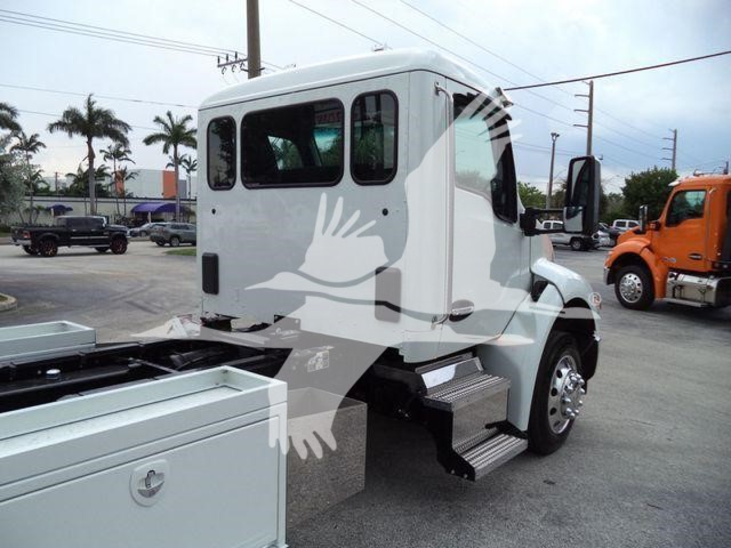 Truck cab rear and side view of a white 2025 Kenworth T280 with steps and side mirrors visible.