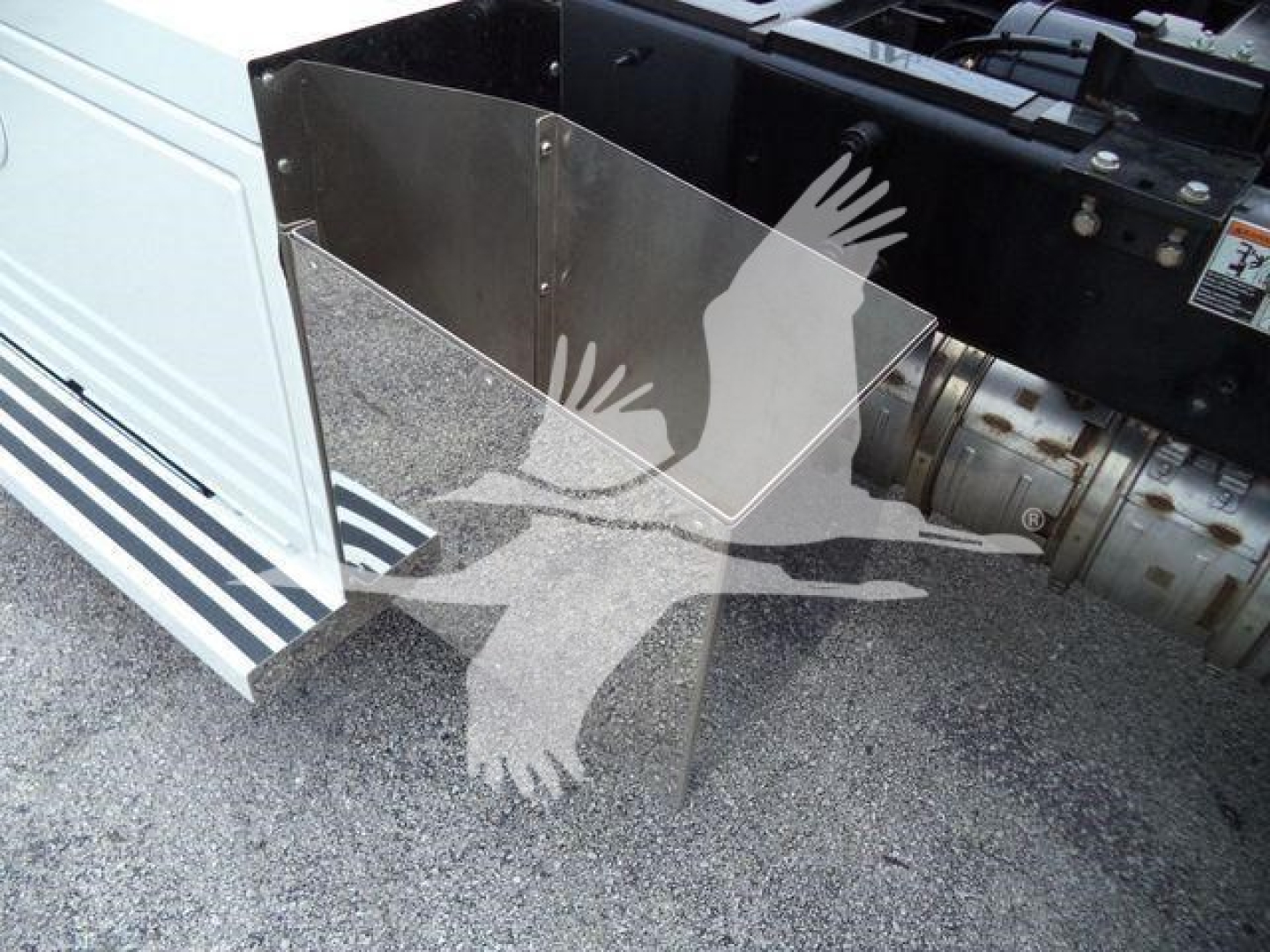Truck side with a metal step/storage box mounted near the cab, showing a reflective stainless panel and part of the chassis and cab exterior.