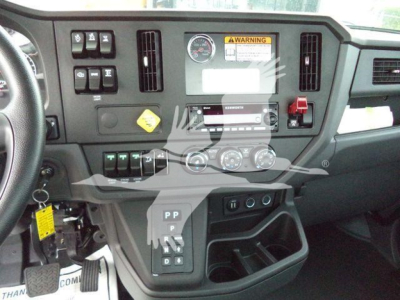 Dashboard view of a 2025 Kenworth T280 showing center console controls, gauges, and gear selector with labels.