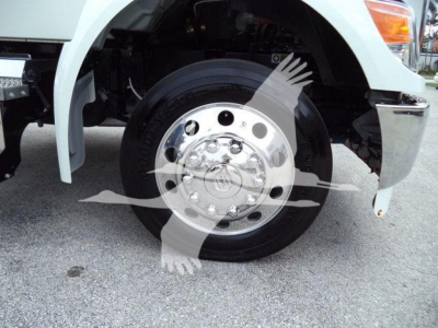Kenworth T280 front wheel and fender showing front wheel hub with chrome lug nut cover and tire; partial bumper and white body panel visible.
