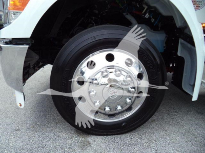 Front wheel of a white 2025 Kenworth T280 with chrome hub, showing wheel and tire details in a rollback truck context.