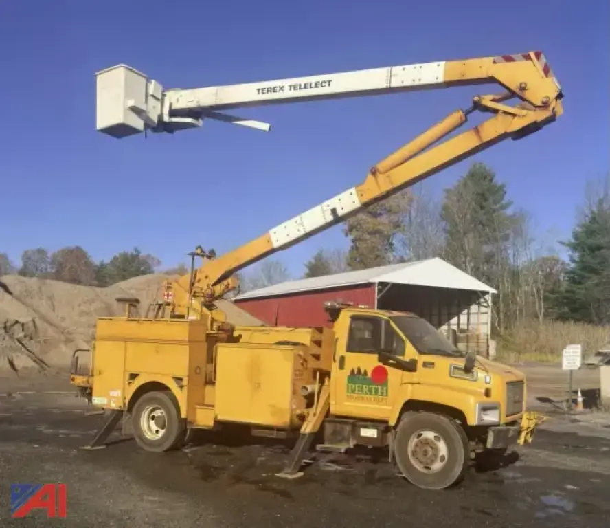 GMC TopKick C7500 utility truck with boom lift in extended position and bucket elevated, yellow service body with equipment compartments.