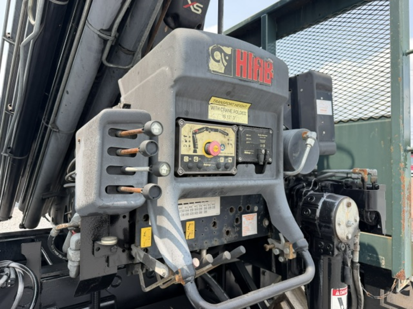 Crane truck control panel with Hiab branding and multiple levers, labels, and a yellow warning sticker visible on the control box.